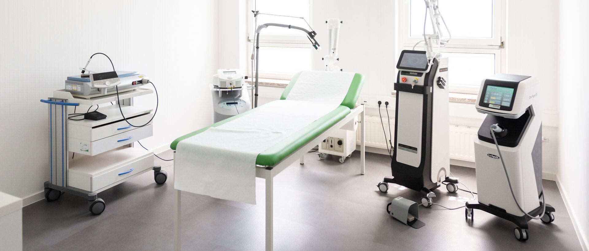 Innenaufnahme Behandlungsraum der Akademie bei intros Medical Laser, die Patientenliege und Lasergeräte sind zu sehen