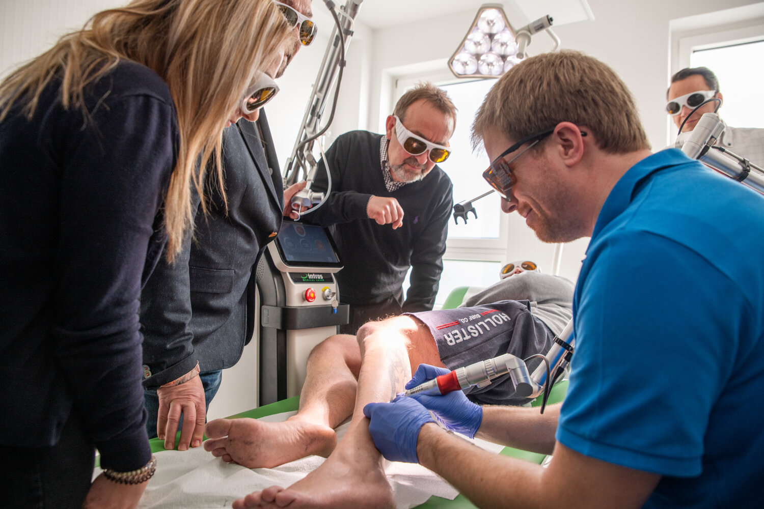 Workshop in der intros Akademie zum Thema Tattooentfernung mit dem Laser, Arzt entfernt Tattoo am Unterschenkel eines Mannes