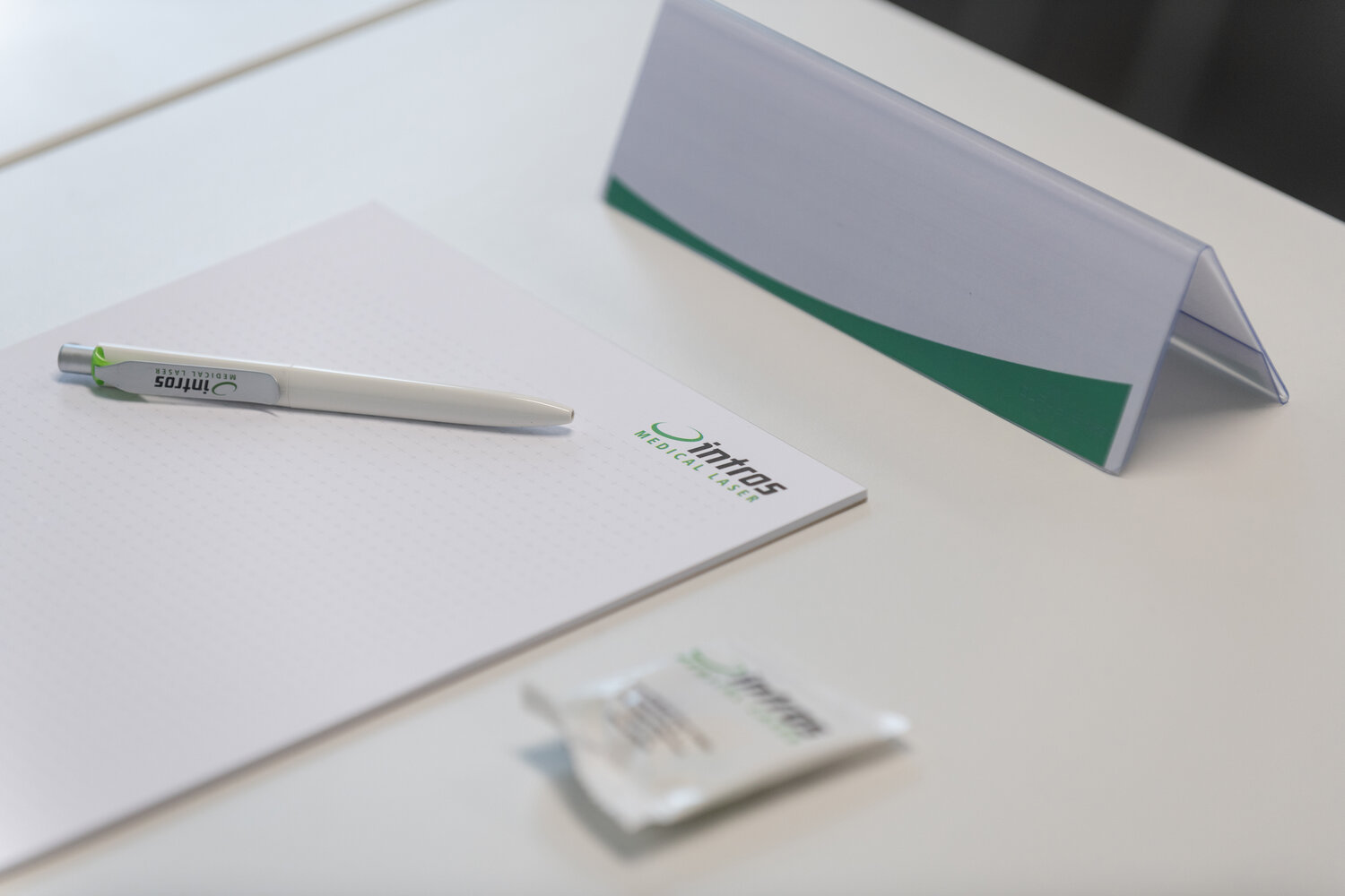Briefbögen, Namenschilder und ein Kugelschreiber mit dem Logo des Firma intros auf einem Schreibtisch