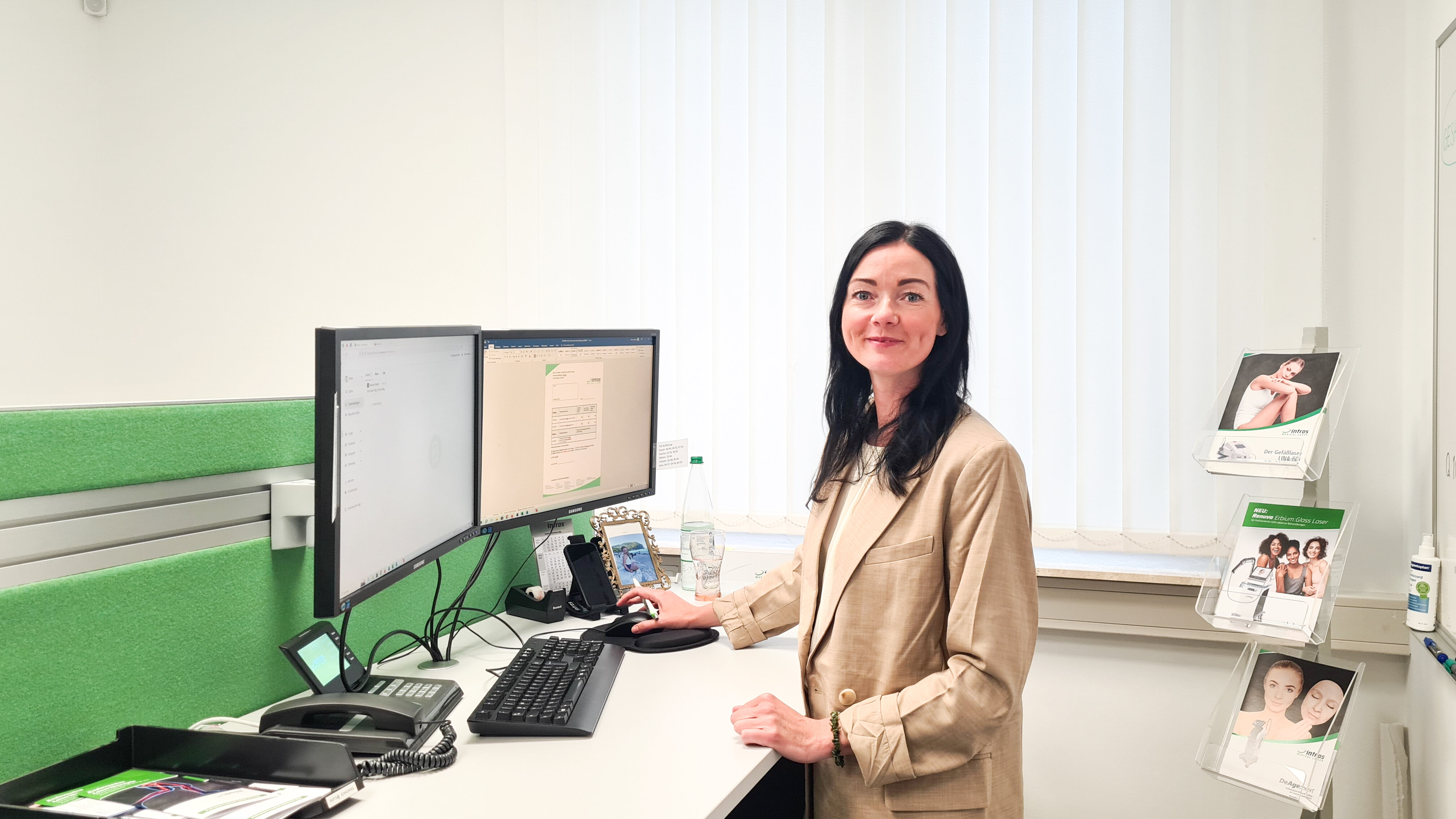 Mitarbeiterin von intros Medical Laser an seinem Schreibtisch, sie lächelt freundlich in die Kamera