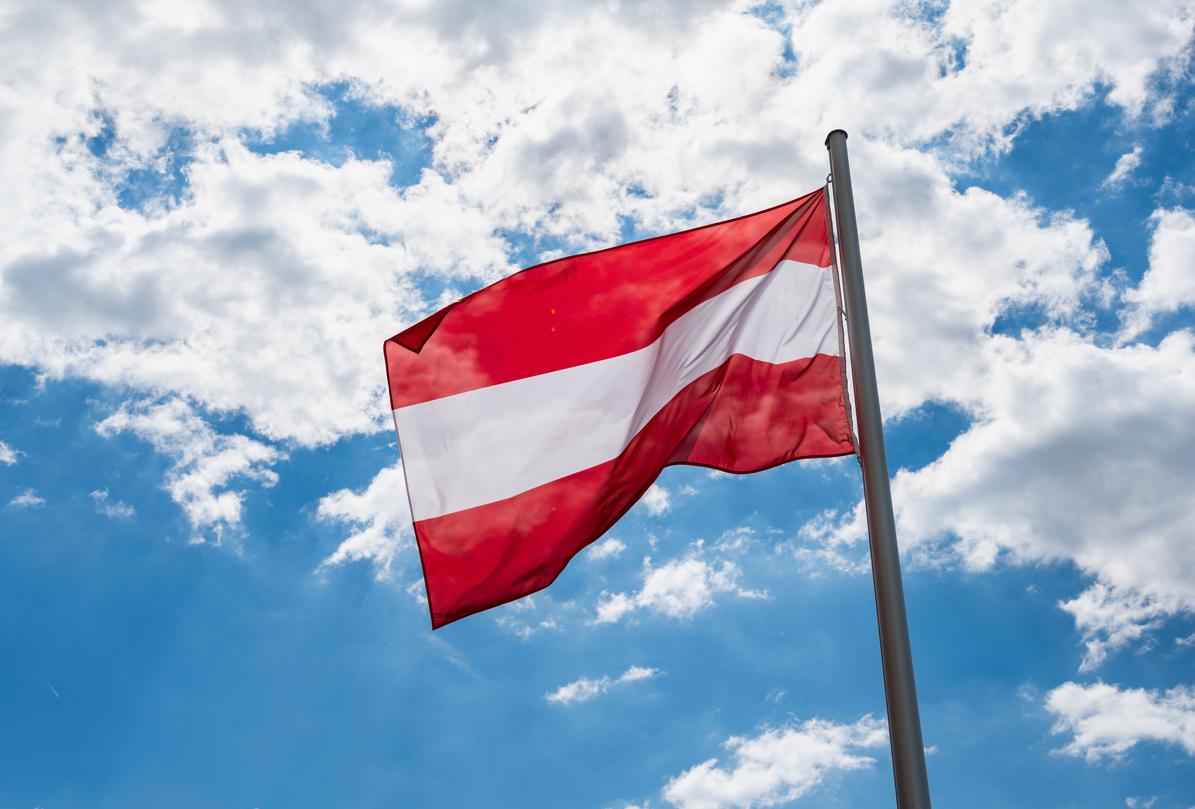 Flagge Österreichs vor blauem Himmel mit leichten Wolken